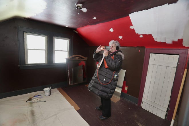 Laura Speaks takes photos of rooms at her Akron rental property to document the conditions a tenant and then squatters left behind. The room had been painted multiple colors by the inhabitants. [Karen Schiely/Beacon Journal]