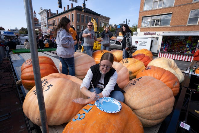 Oct 18, 2023; Circleville, OH, USA; Rebekah Jenkins, 17, a Senior at Logan Elm paints a pumpkin with itÕs weight during the Pumpkin Show.