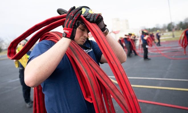 Feb 27, 2024; Reynoldsburg, OH, United States; Jakob Baxter gathers a firehose after training in a technique on how to handle the hose after use during a training session at the Division of State Fire MarshalÕs Ohio Fire Academy. Baxter is learning the techniques in order to work as a volunteer firefighter.