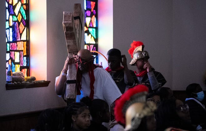 Mar 24, 2024; Columbus, OH; Revered Fred Booker dressed as Jesus carries a reproduction of the cross during an Easter performance at the Family Missionary Baptist Church on Palm Sunday. The performance reenacted several scenes from the crucifixion, last dinner and resurrection of Jesus.