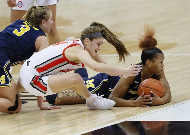 Ohio State Buckeyes guard Jacy Sheldon (4) dives to the court while scrambling for a loose ball with Michigan Wolverines guard Akienreh Johnson (14) during the fourth quarter of the women's college basketball game at Value City Arena in Columbus on Thursday, Jan. 21, 2021. Ohio State won 81-77.
