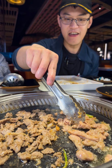 Mar 28, 2024; Columbus, Ohio, USA; Felix Zhao, an assistant manager at PJ Hot Pot on the Northwest Side, grills chicken and beef right at the dining table.