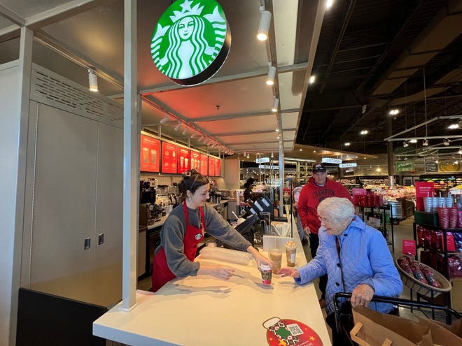 A Starbucks employee gives a guest a small pumpkin latte with whipped cream at the Starbucks in South Lyon, Michigan on Nov. 16, 2023.
