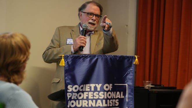 April 17, 2024; Columbus, Ohio, USA; Pointing out to the crowd where they can find memorial bracelets, TC Brown accepts an award on behalf of his late wife Mary Yost at the 2024 Society of Professional Journalists Central Ohio Chapter annual Founders Day ceremony. Yost was a Columbus Dispatch reporter and editorial page editor who died in January 2024. The event was held at the Columbus Center for Architecture and Design, 50 W. Town St.