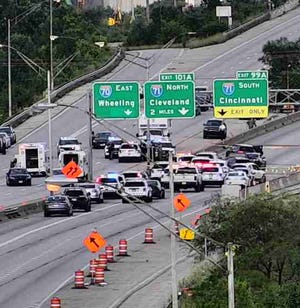 Police vehicles on I-70 at Mound Street near Downtown surround a stolen Porsche Cayenne SUV, just beneath the I-71 South sign, as officers responded to a Columbus police officer shot by robbery suspects Thursday afternoon. Eight officers were involved in the incident, but police have not identified them, citing Marsy's Law.